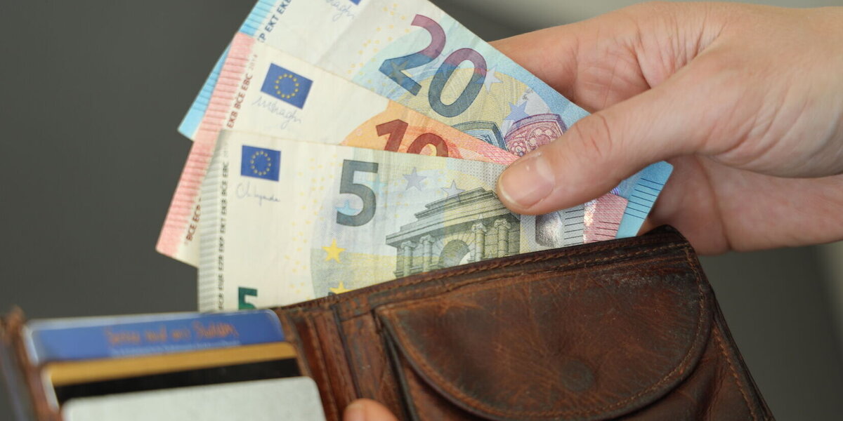 Person, die Geldscheine aus einem Geldbeutel nimmt