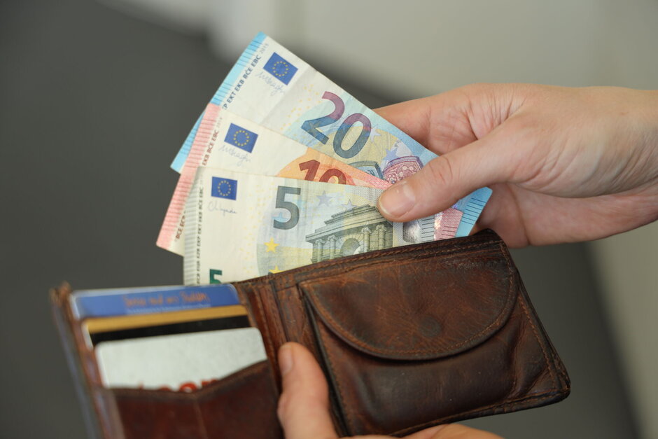 Person, die Geldscheine aus einem Geldbeutel nimmt