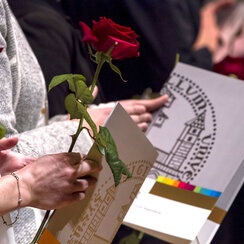 Absolventenfeier: Studierende halten Urkundenmappen im Design der Universität Regensburg und langstielige rote Rosen in den Händen. 