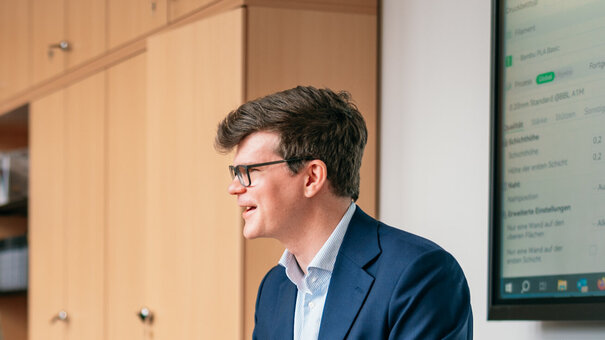 Vier Männer sitzen um einen Besprechungstisch in einem Büro und diskutieren.