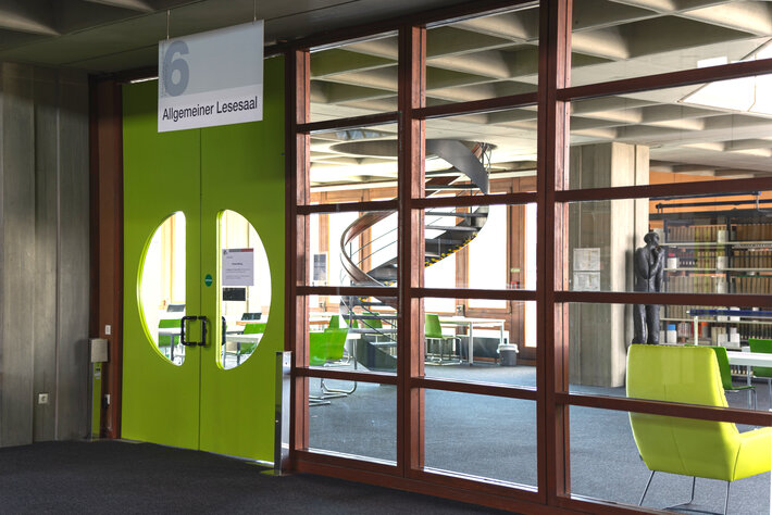 Eingang in den Allgemeinen Lesesaal der Universitätsbibliothek Regensburg; durch die bodenlangen Glasscheiben sieht man in den sonnigen, hellen Lesesaal. (öffnet Vergrößerung des Bildes)