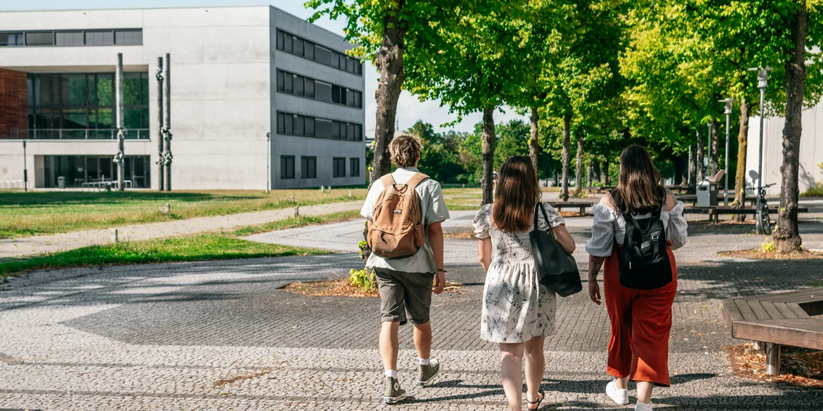 Eine Gruppe Studierender geht auf das Vielberth-Gebäude am Campus der Universität Regensburg zu.