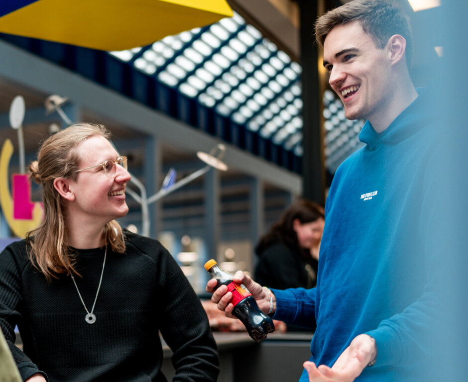 Drei Studenten unterhalten sich lachend in einer Cafeteria an der Universität Regensburg