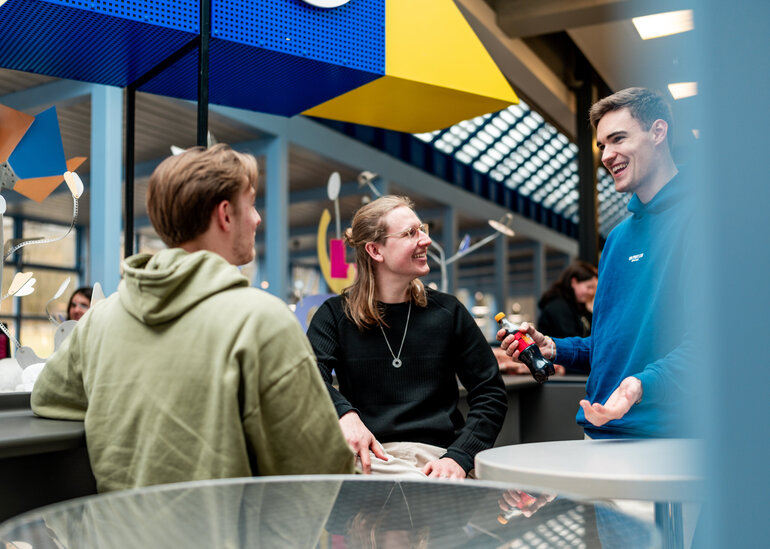 Drei Studenten unterhalten sich lachend in einer Cafeteria an der Universität Regensburg