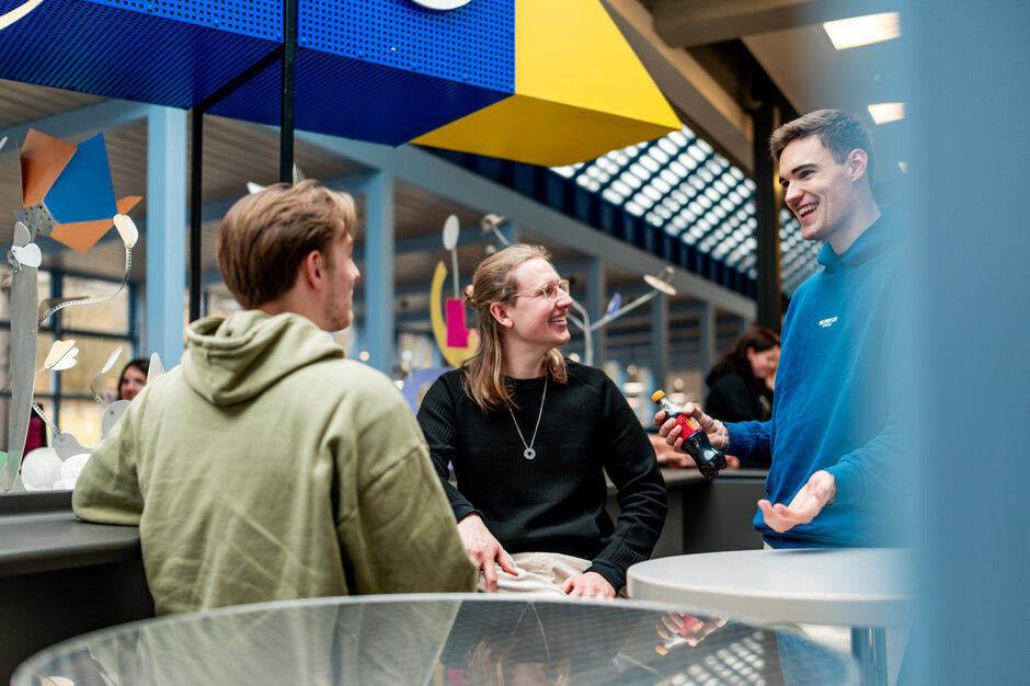 Drei Studenten unterhalten sich lachend in einer Cafeteria an der Universität Regensburg
