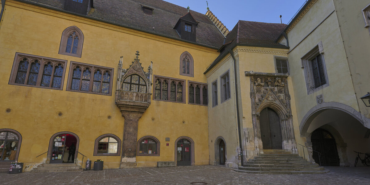 Die in Gelb-Tönen gehaltene, mittelalterliche Fassade des Alten Rathauses in Regensburg.