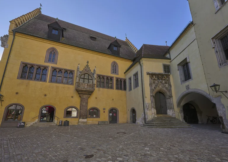 Die in Gelb-Tönen gehaltene, mittelalterliche Fassade des Alten Rathauses in Regensburg.