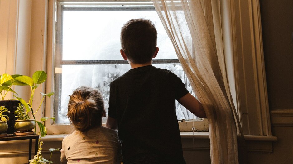 Two children from behind looking out of the window
