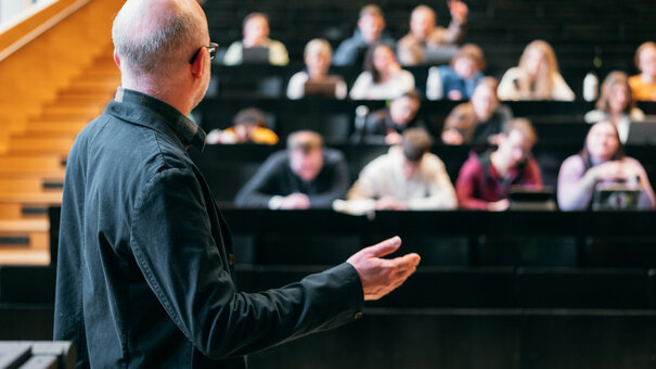 Ein Dozent hält in einem Hörsaal einen Vortrag vor Studierenden.
