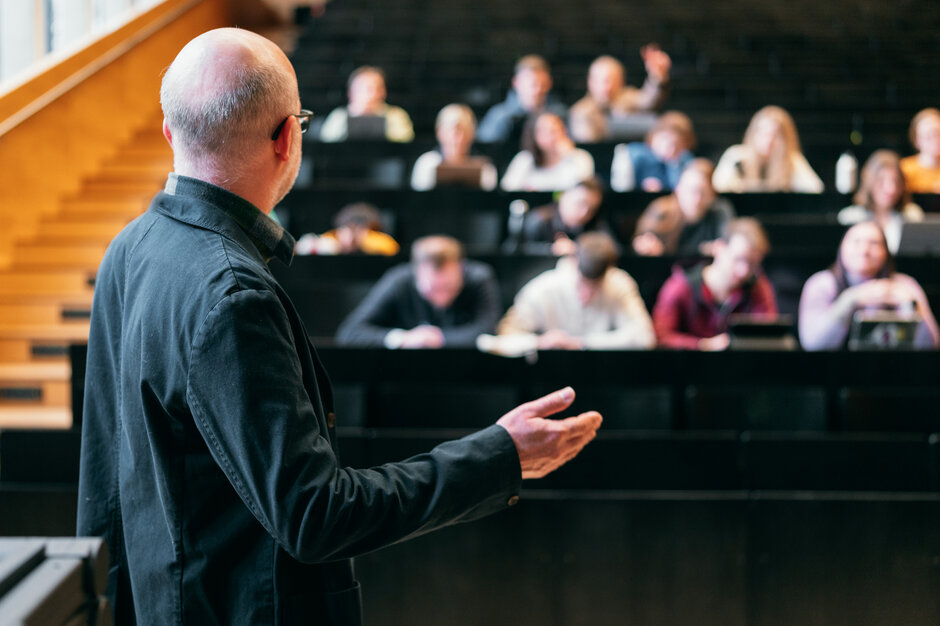Ein Dozent hält in einem Hörsaal einen Vortrag vor Studierenden.
