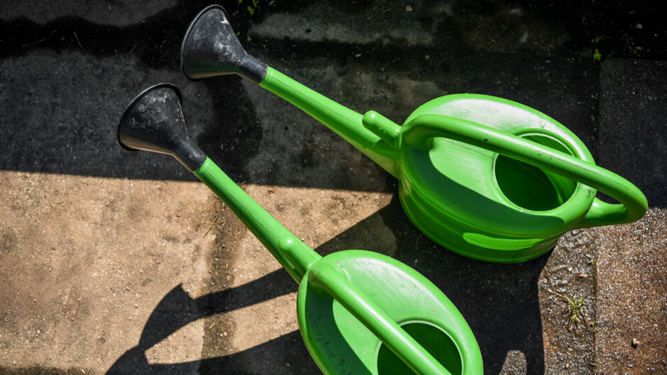 Draufsicht von oben auf zwei grüne Gießkannen aus Plastik.