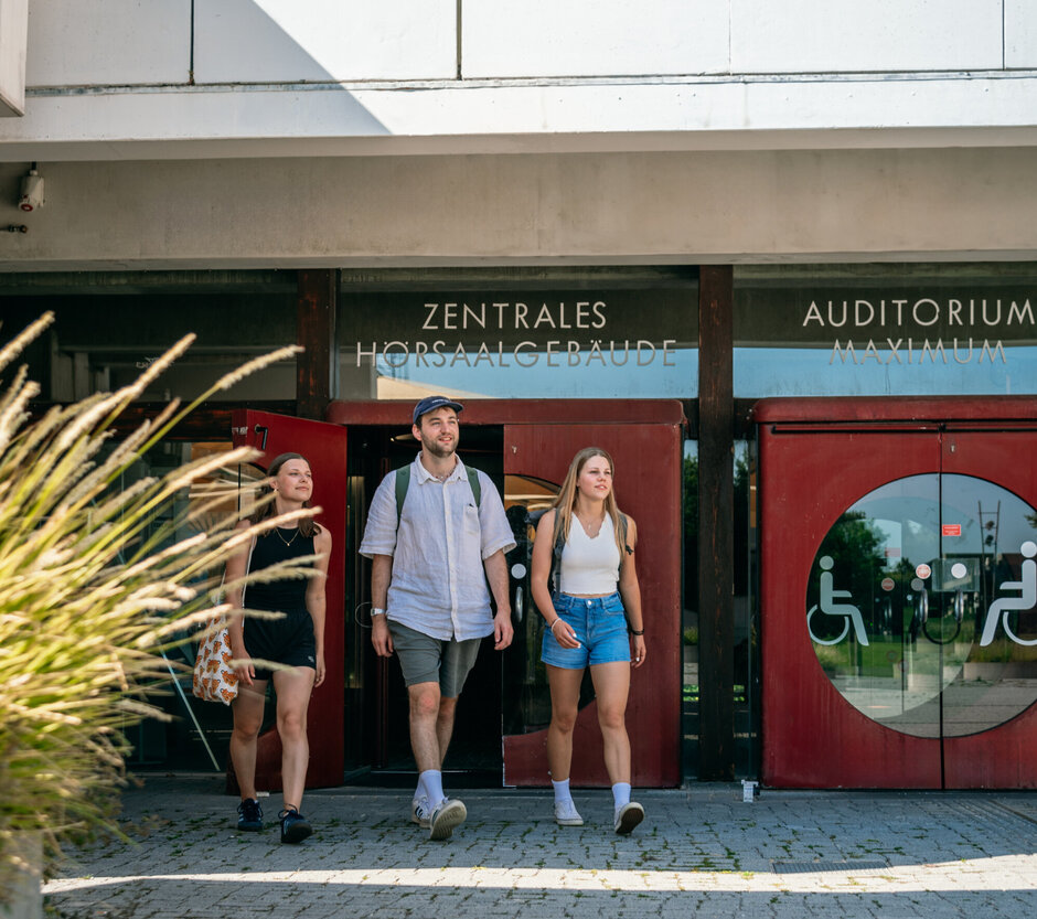 Drei Studierende verlassen das Zentrale Hörsaalgebäude der Universität Regensburg.