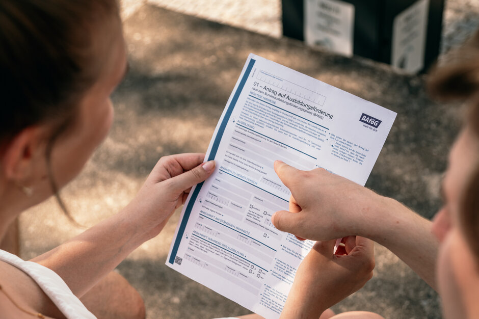 Zwei Studierende sehen sich ein Formular für einen BAföG-Antrag an