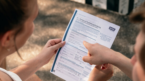 Zwei Studierende sehen sich ein Formular für einen BAföG-Antrag an