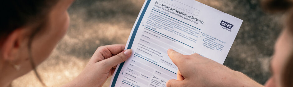 Zwei Studierende sehen sich ein Formular für einen BAföG-Antrag an