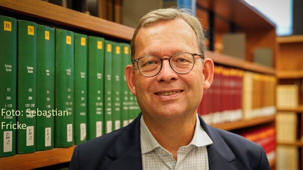 Ein Foto des Lehrstuhlinhabers Prof. Dr. Thorsten Kingreen vor einem Bücherregal.