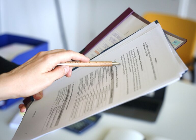 Eine Person zeigt auf ein Dokument.