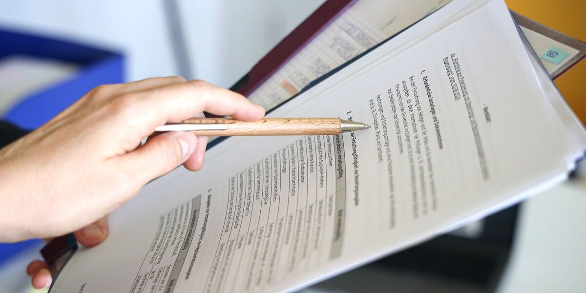 Eine Person zeigt auf ein Dokument.