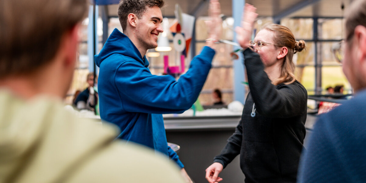 Zwei Studenten klatschen sich mit der Geste "High Five" ab.