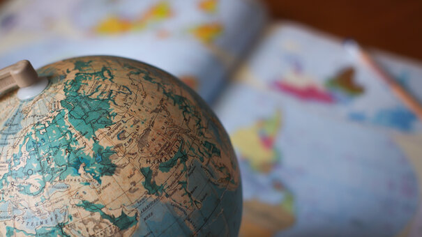 Man sieht einen Globus vor einer Weltkarte