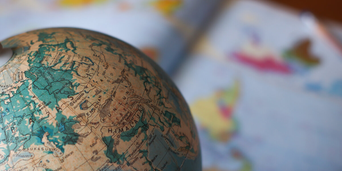 Man sieht einen Globus vor einer Weltkarte