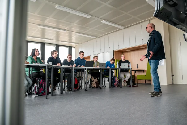 Ein Dozent hält einen Vortrag vor einer Gruppe von Studierenden in einem modern ausgestatteten Seminarraum an der Universität Regensburg