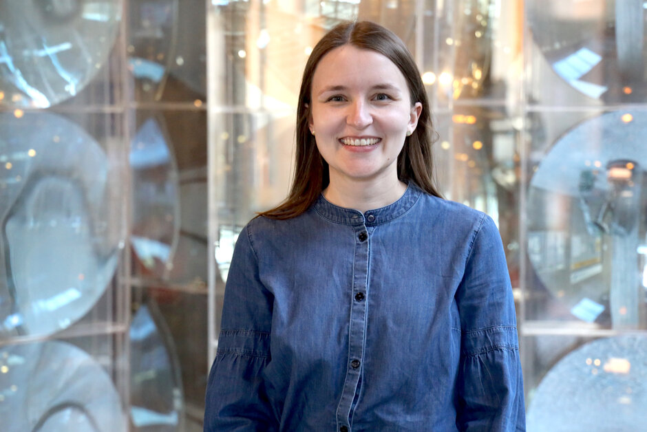 eine junge Frau in blauem Oberteil vor unscharfem Hintergrund