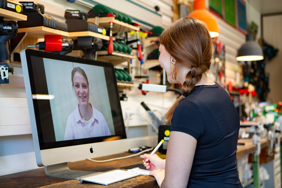 Frau vor Computerbildschirm, auf dem eine andere Frau zu sehen ist.