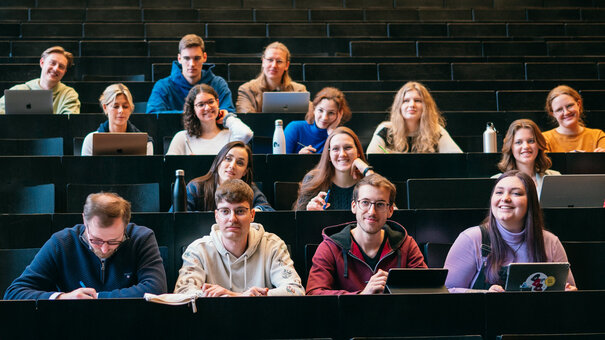 Ein Dozent spricht in einem Hörsaal zu Studierenden.