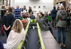 Viele stehende und sitzende Menschen im Ausstellungsraum