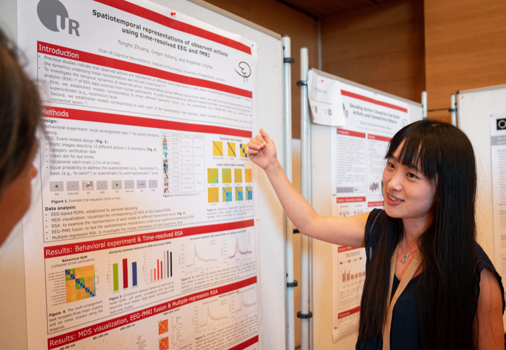 A young woman explains a scientific poster.