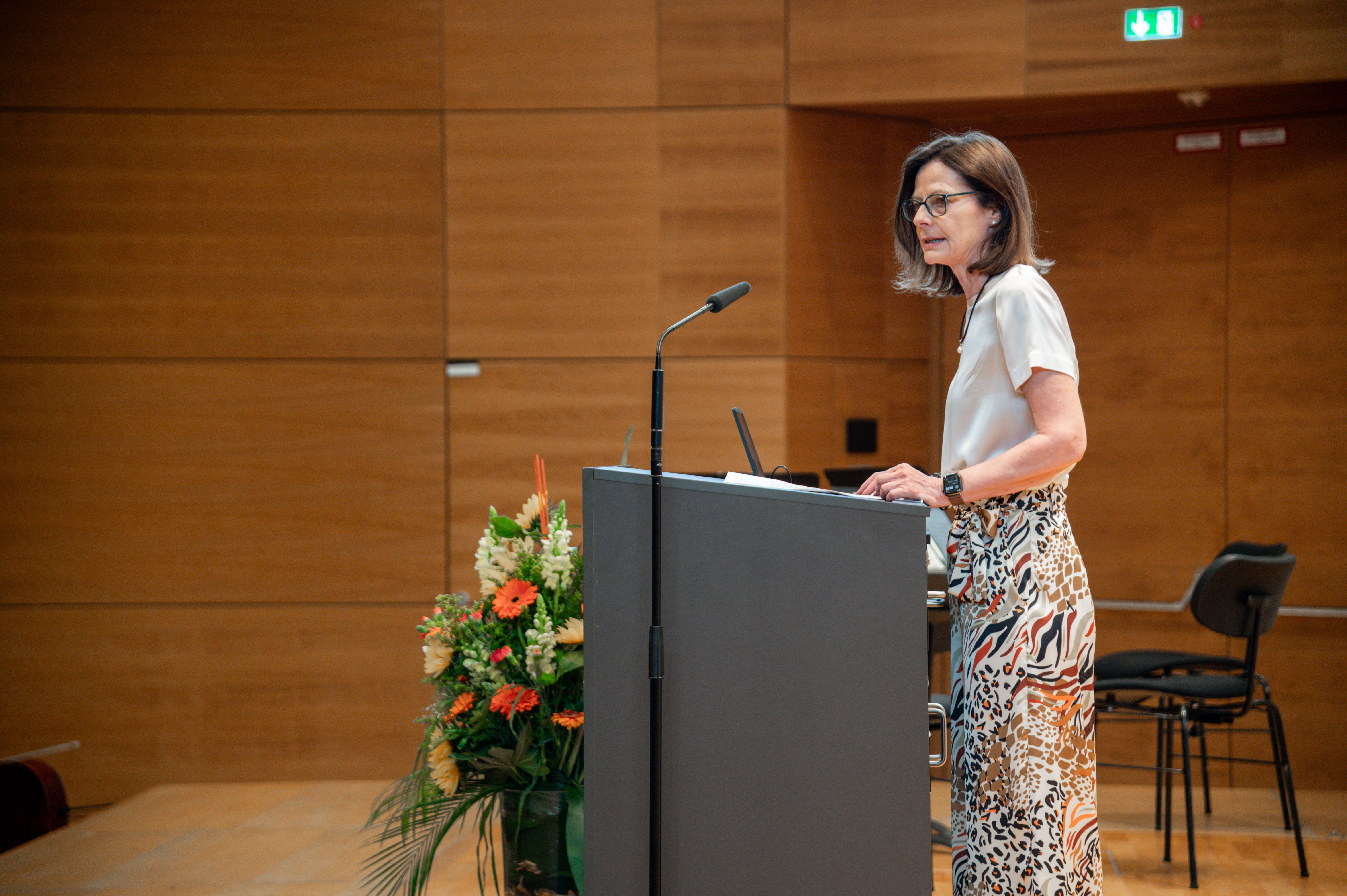 Frau mittleren Alters steht am Rednerpult und spricht. (öffnet Vergrößerung des Bildes)