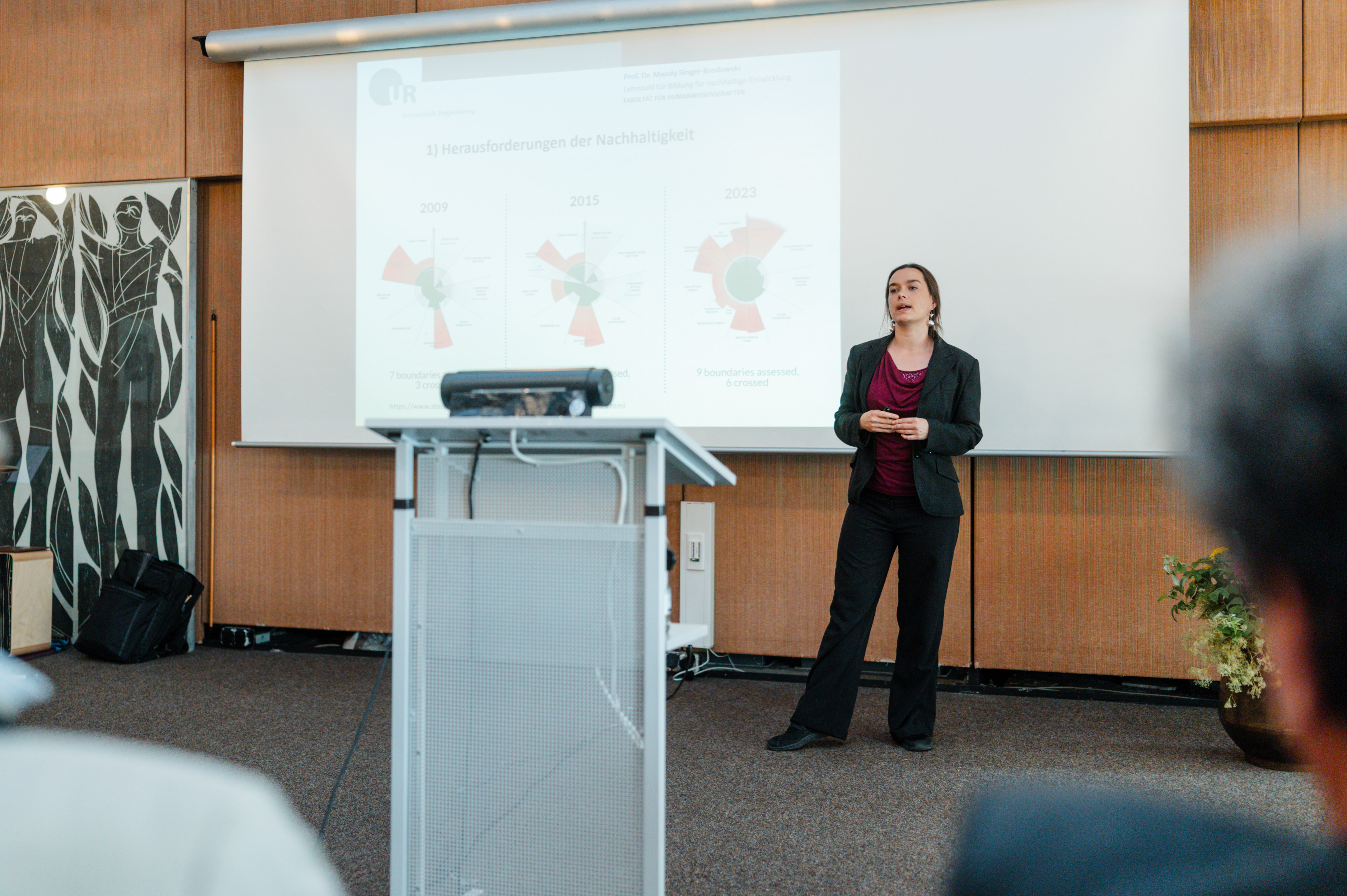 Ein Frau steht vor einer Powerpoint-Folie und hält einen Vortrag. (öffnet Vergrößerung des Bildes)