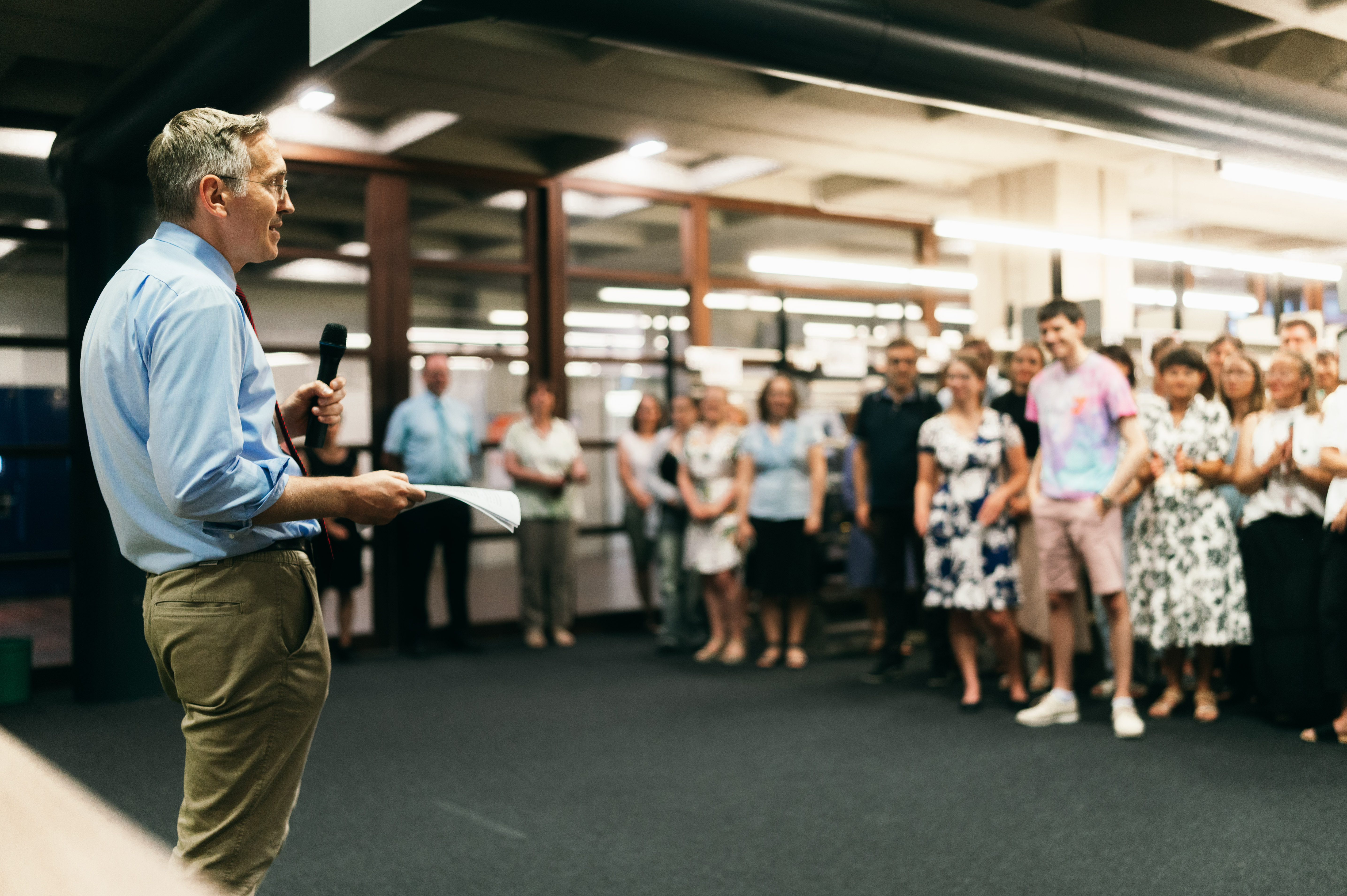 Mann mit Mikrofon vor stehender Personengruppe. (öffnet Vergrößerung des Bildes)