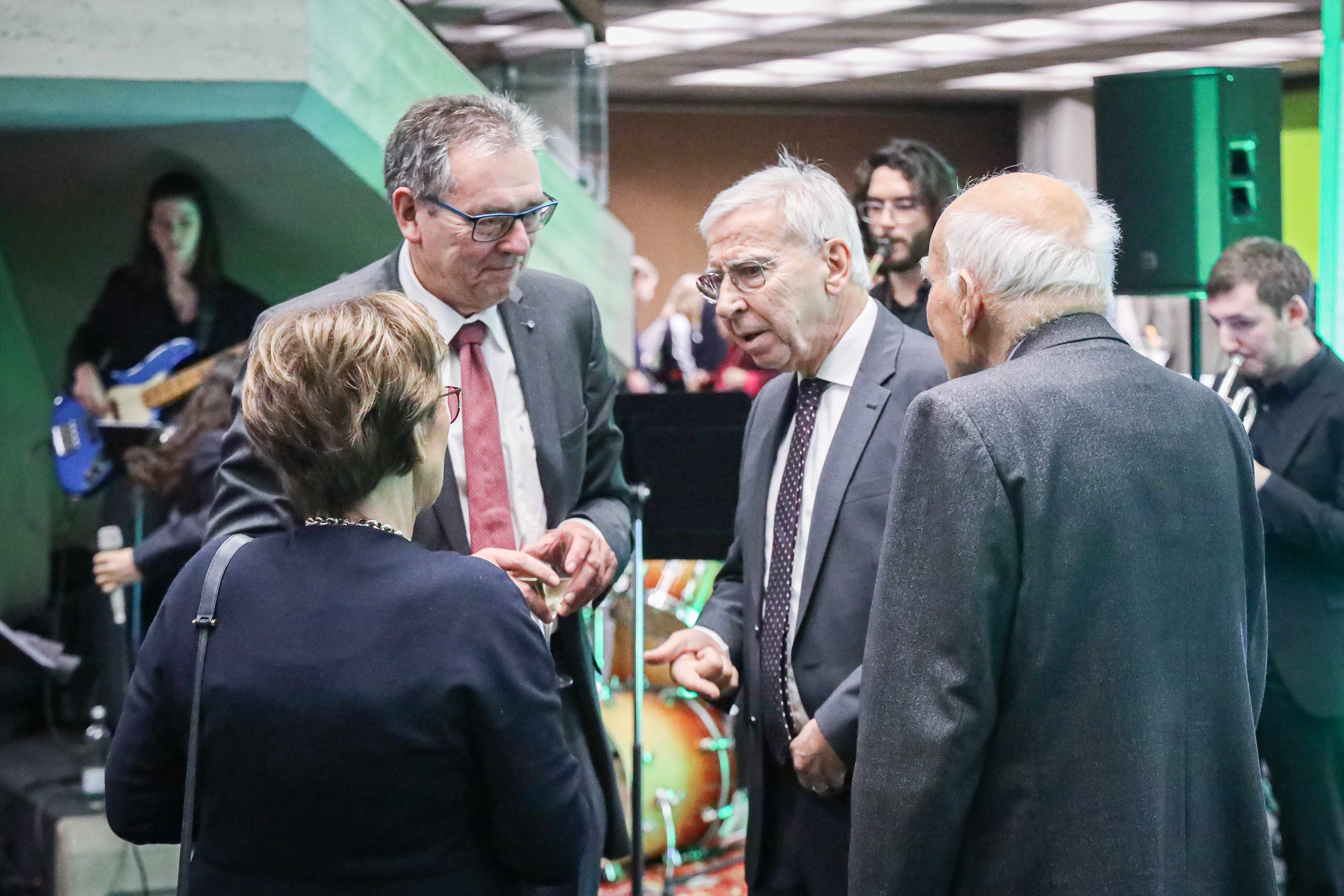 Drei ältere Männer und eine Frau unterhalten sich in einer Viererrunde. (öffnet Vergrößerung des Bildes)